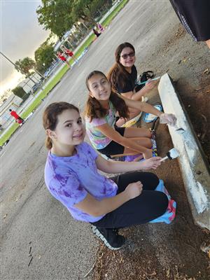 Students painting a parking lot divider white.